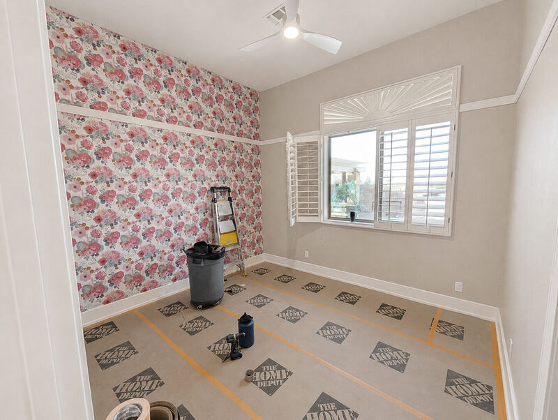 The room as we found it: a pink cabbage-rose paper on the accent wall, everything else builder-beige