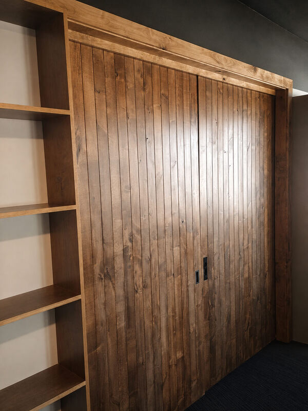 Flush black pull in a walnut plank door