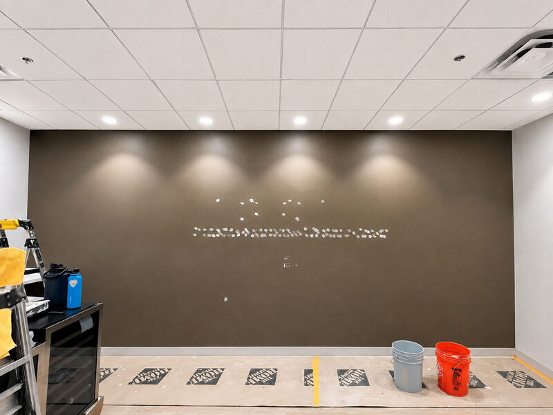 Before: signage removed, anchor holes patched in a line