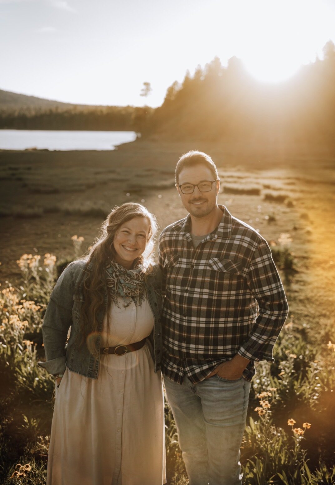 Josh Sheppard and Amber Gastelum, the brother and sister behind Wallwright Studio, standing in a meadow at sunset.